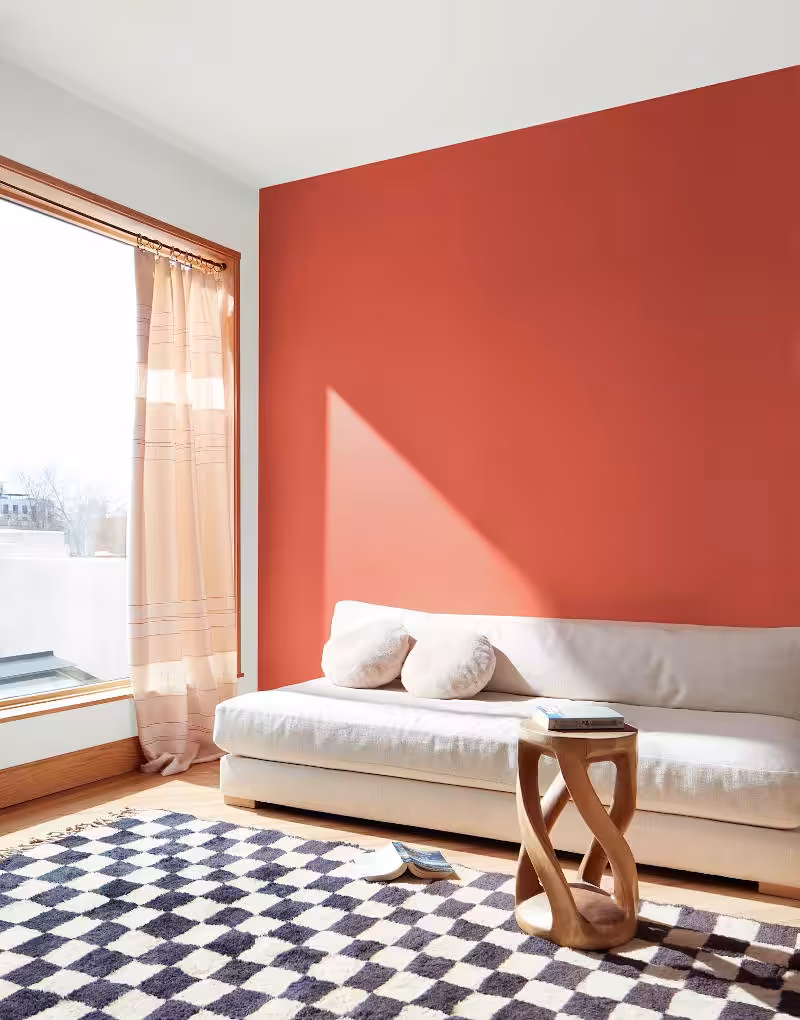 bright room with sunny window and accent wall painted raspberry blush behind white sofa