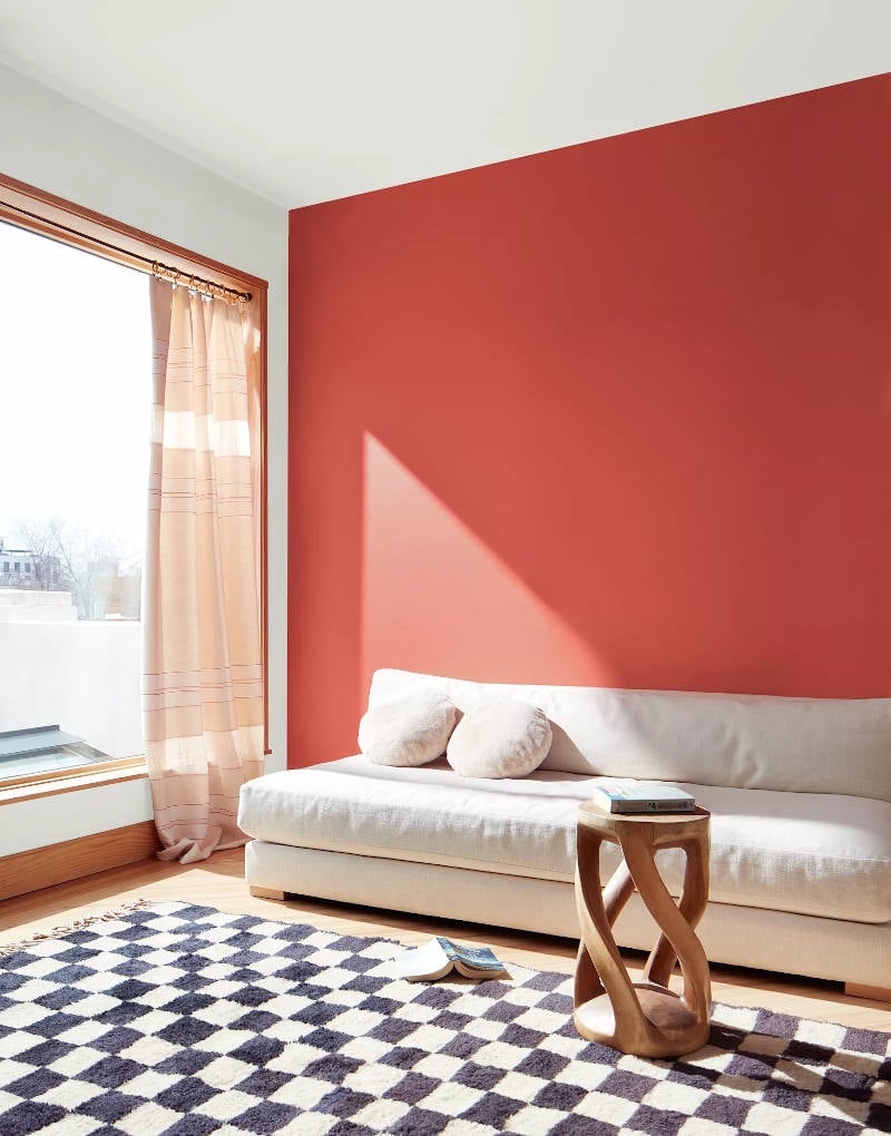 bright room with sunny window and accent wall painted raspberry blush behind white sofa