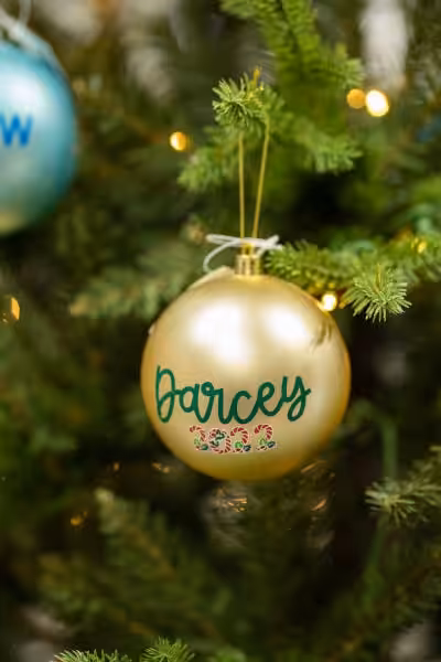 gold coloured custom christmas tree ornament with Darcey 2022 on it