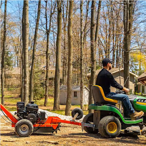man driving lawn tractor with dk2 opg888e model stump grinder hitched to tractor