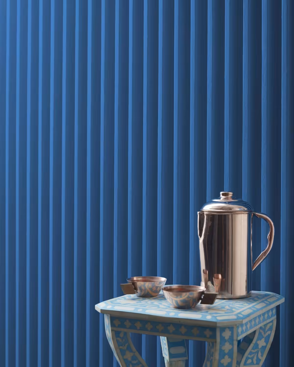 athens blue colour painted wall with small table in front and teapot sitting on table