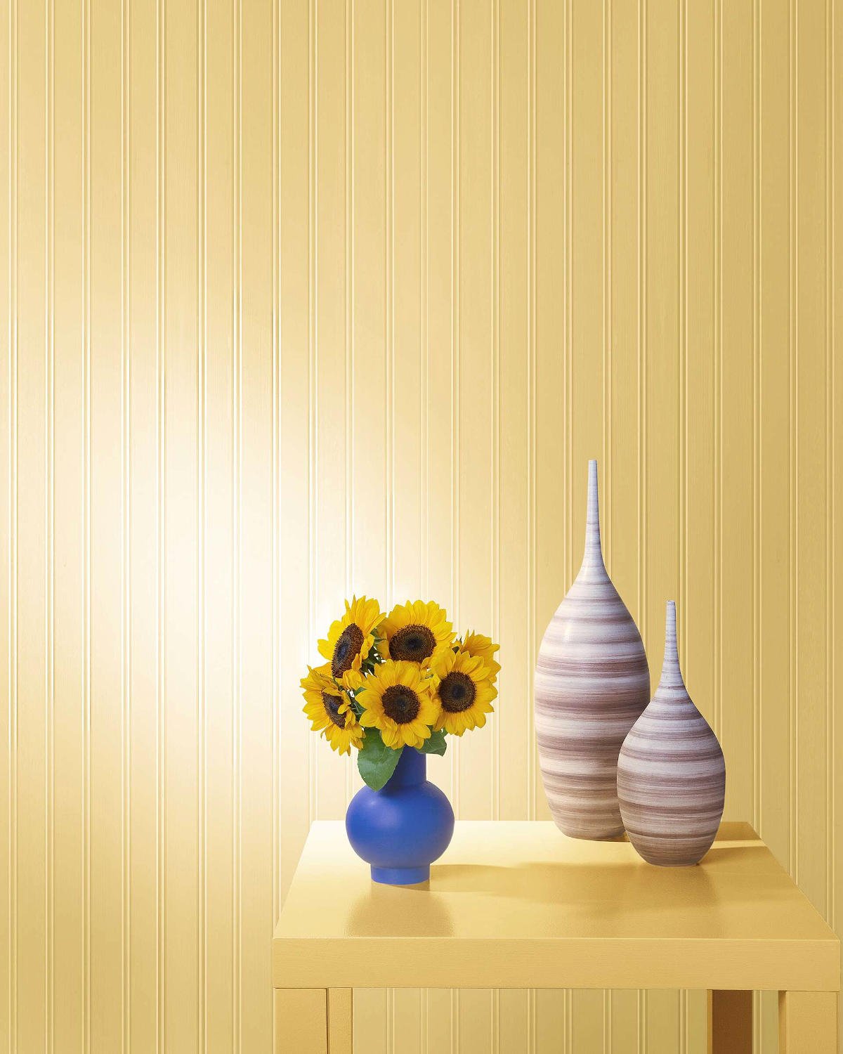 a wall painted in benjamin moore's honebee colour with a table in front and a vase of miniature sunflowers