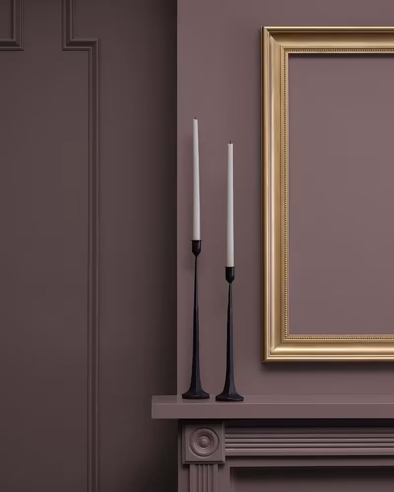 wall and mantle painted in benjamin moore cinnamon slate with two white candles on mantle
